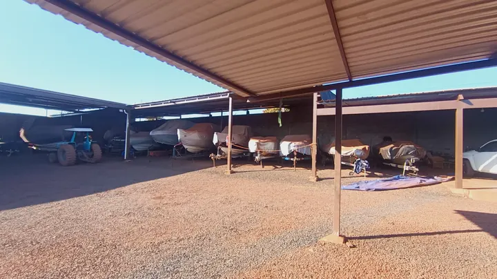 Barcos em reboque guardados dentro do galpão, cobertos por lona